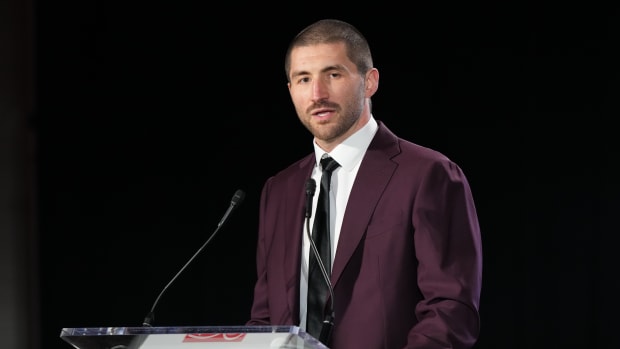 JC Tretter talks into a microphone standing at a podium